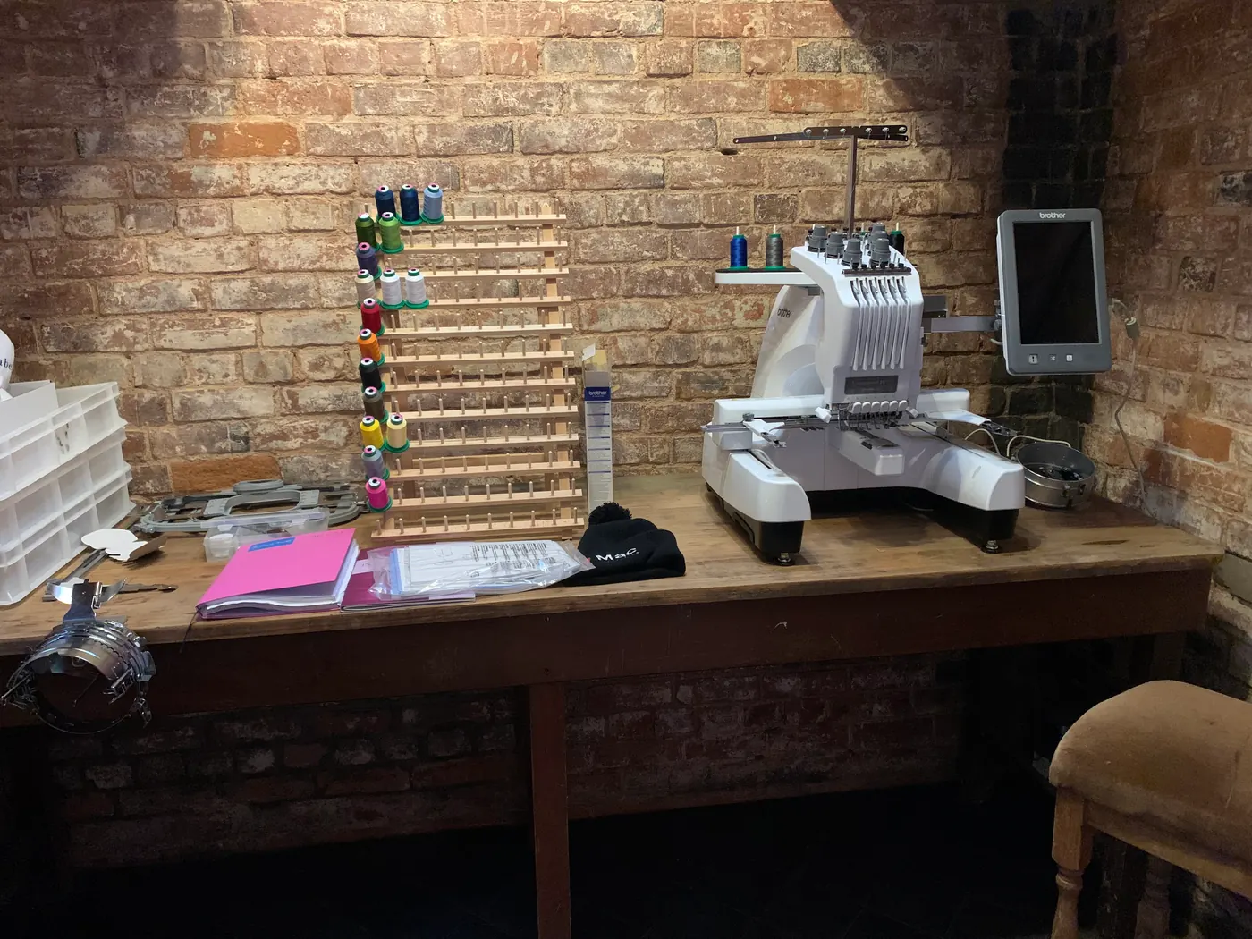 An embroidery machine set up on a workbench with reels of thread